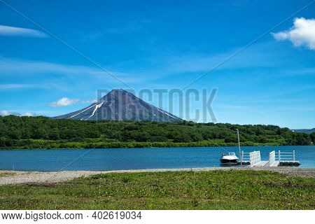 View From The Shore Of The Kuril Lake To The Ilyinsky Volcano With A Pier For Pleasure Boats And A W