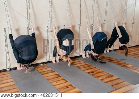 Lyengar Female Group Of Yogi Practicing Calisthenics Exercise In Yoga Studio Hanging On A Wall With 