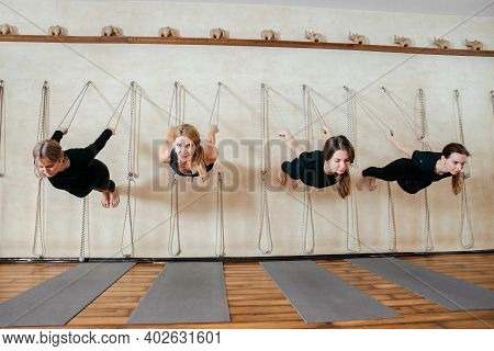 Lyengar Female Group Of Yogi Practicing Calisthenics Exercise In Yoga Studio Hanging On A Wall With 
