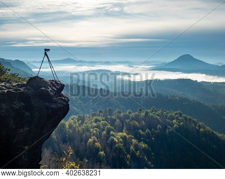 Camera On Tripod Photographing Foggy Mountains, Blue Sky And Foggy Landscape. Mountains Background. 