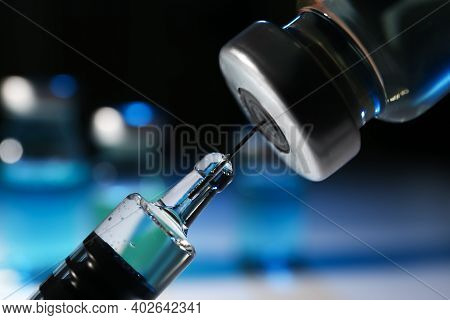 Filling Syringe With Vaccine From Vial On Blurred Background, Closeup