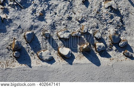 Snowy Parking From Above. Large Stones Delimit The Parking Space. A Barrier Made Of Giant Tribes Tha