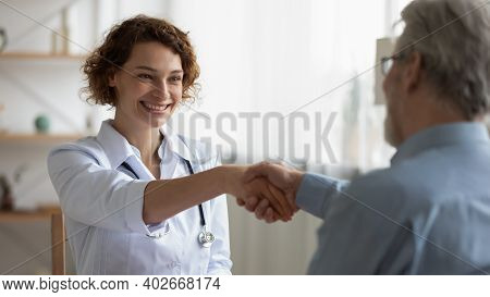 Happy 35s Young Female Physician Shaking Hands With Patient.
