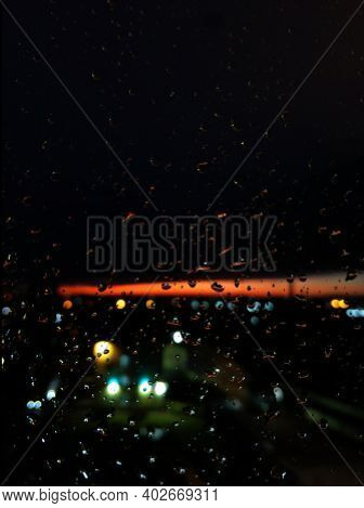 Raindrops On Glass. Livin During Sunset. Night Sky With A Bright Orange Stripe.