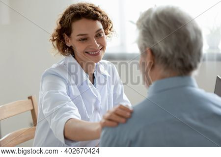 Happy Young 30s Physician Doctor Supporting Elderly Patient.