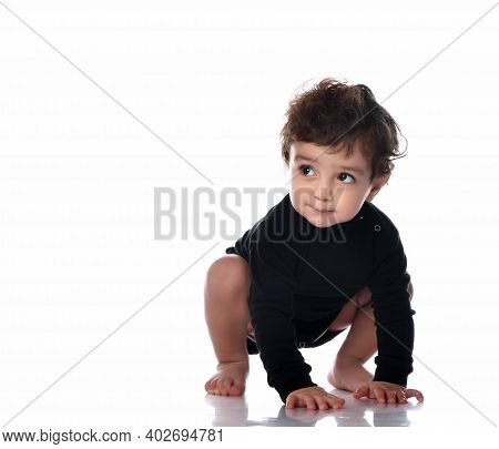 Baby Boy Child Standing On All Fours. Barefoot Little Toddler Kid Wearing Black Jumpsuit Crawling On