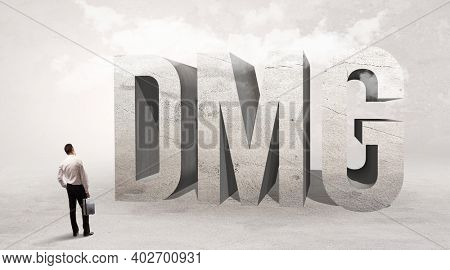 Rear view of a businessman standing in front of DMG abbreviation, attention making concept