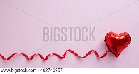 Love Concept. Red Balloon In The Shape Of Heart With Festive Red Bant On Pink Background Top View Fl