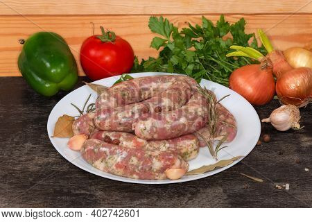 Raw Homemade Pork Sausages, Semifinished Prepared For Further Grilling, On A White Dish On A Black S