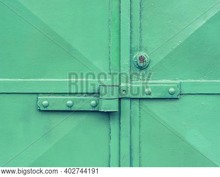 Locked Green Warehouse Metal Door. Detail View To Locked Latch Welded Into Double Doors Frame.
