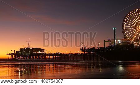 Twilight Waves Against Classic Illuminated Ferris Wheel, Amusement Park On Pier In Santa Monica Paci