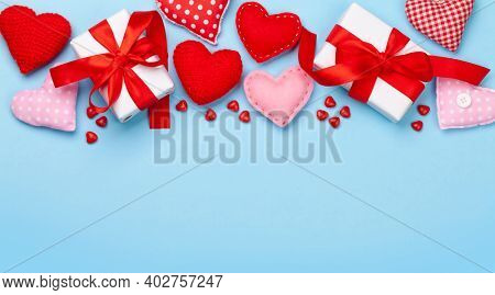 Valentines day greeting card template. Gift boxes, heart decor and candy sweets over blue background. Top view flat lay with copy space