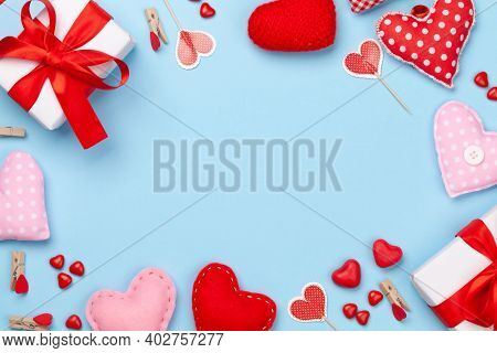 Valentines day greeting card template. Gift boxes, heart decor and candy sweets over blue background. Top view flat lay with copy space