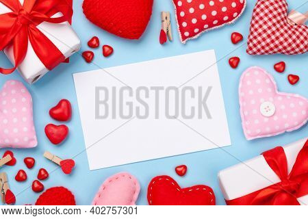 Valentines day greeting card template. Gift boxes, heart decor and candy sweets over blue background. Top view flat lay with copy space