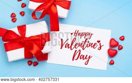 Valentines day greeting card. Gift boxes and heart candy sweets over blue background. Top view flat lay