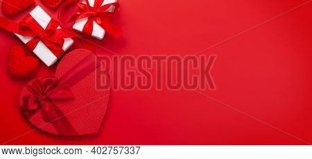 Valentines day greeting card template. Gift boxes and heart shaped decor over red background. Top view flat lay with copy space