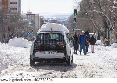 Madrid, Spain - January 10, 2021: A Car Covered In Snow Tries To Slowly Cross Dr. Esquerdo Street, O