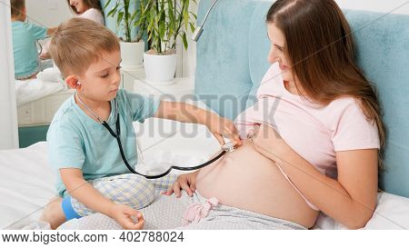 Cute Boy Playing In Doctor And Listening To Pregnant Mother Heartbet With Stetchoscope. Concept Of H