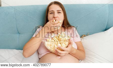 Pergnant Woman Feeling Very Hungry Grabing Handful Of Popcorn And Putting It In Mouth.