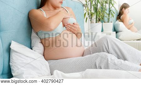 Closeup Of Pregnant Woman In Bra Checking Her Aching Breast For Breast Cancer. Concept Of Pregnancy 