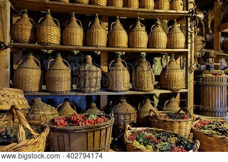 Bottles with wine and baskets with grapes in old wine cellar