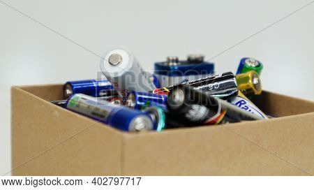 A Cardboard Box On A White Background Full Of Used Household Aa, Aaa, Pp3 Alkaline Batteries Collect
