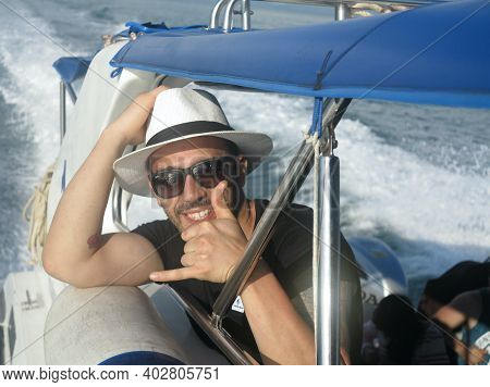 Close Up Portrait Of An Attractive Smiling Man Wearing A Hat On A Yacht. Attractive Man In Sunglasse