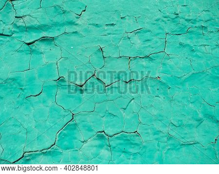 Close-up Old Green Cracked Paint. The Texture Of The Old Emerald Paint With Cracks. Dried In The Sun