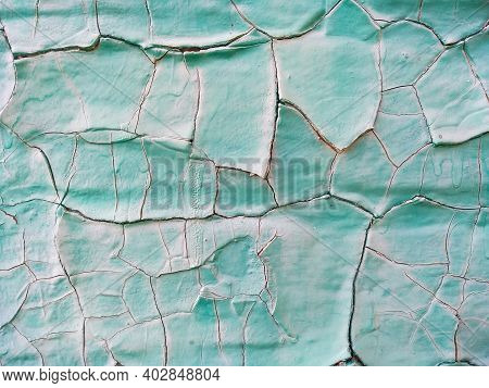 Close-up Old Green Cracked Paint. The Texture Of The Old Emerald Paint With Cracks. Dried In The Sun