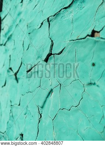 Close-up Old Green Cracked Paint. The Texture Of The Old Emerald Paint With Cracks. Dried In The Sun