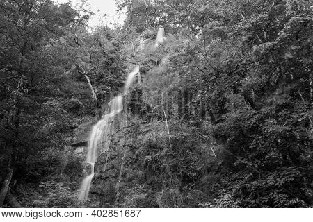 Long Exposure Of The Waterfall Flowing Over The Cliff At Canonteign Falls In Dartmoor