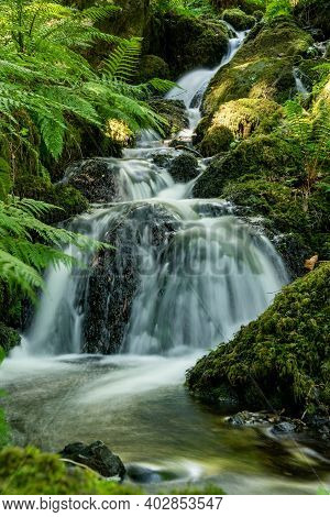 Long Exposure Of A Waterfall Flowing Through The Woods At Canonteign Falls In Dartmoor