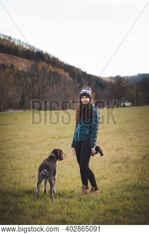 Gorgeous Smiling Woman Is On A Walk With Her Dog Bohemian Wire-haired Pointing Griffon. The Domestic