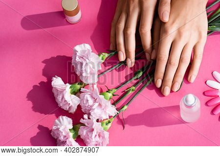 Top View Of Female Hands Near Carnation Flowers, Palette Of Fake Nails, Vials With Cuticle Remover A