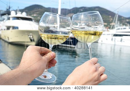 Paar Weingläser in den Händen gegen den Yacht-Pier von La Spezia, Italien