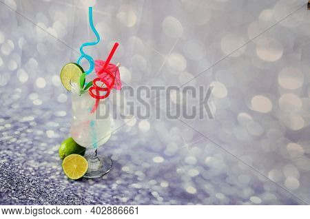 A Glass Of Clear Nectar With Ice And A Slice Of Lime Stands On A Gray Shiny Background.
