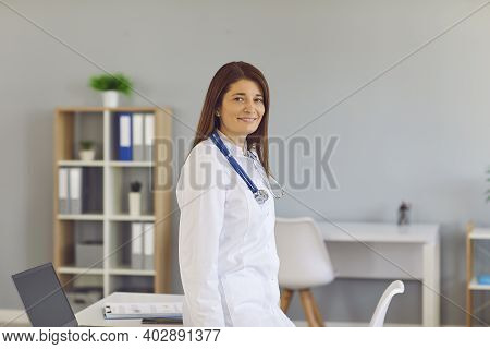 Smiling Young Woman Doctor Therapist In White Medical Uniform Looking At Camera In Clinic