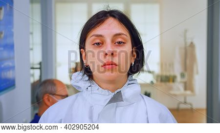 Close Up Of Exhausted Nurse In Dental Office Looking On Camera Wearing Ppe Suit Without Face Shield 