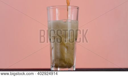 Close Up Of Pouring Cola In A Long Transparent Glass With Ice And Bubbles. Action. Soda Soft Drink I