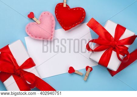 Valentines day greeting card template. Gift boxes and heart shaped decor over blue background. Top view flat lay with copy space
