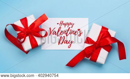 Valentines day greeting card. Gift boxes over blue background. Top view flat lay