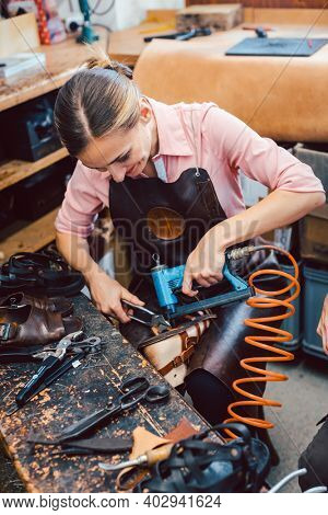 Cobbler woman repairing a shoe fixing the sole