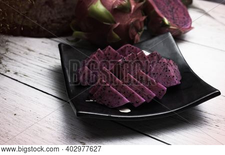Sliced Of Red Dragonfruit Put On Black Dish,blurry Light Around