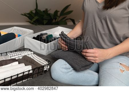 Vertical Storage Of Clothing.women Organize Clothes In A Modern Bedroom. Women Sorting Clothes In Ba