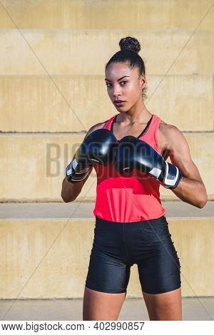 Vertical Portrait Of An Afro American Female Athlete Wearing Black Boxing Gloves And Standing In Def