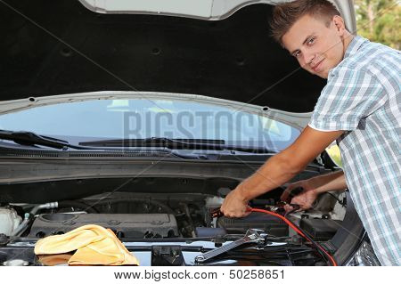 Young driver uses battery jumper cables to charge dead battery