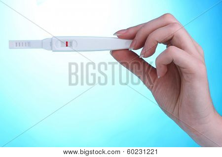 pregnancy test in hand on blue background