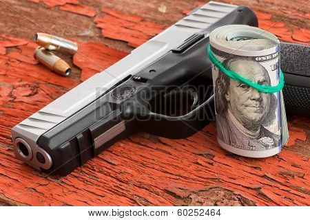 Gun With A Roll Of 100 Dollar Banknotes