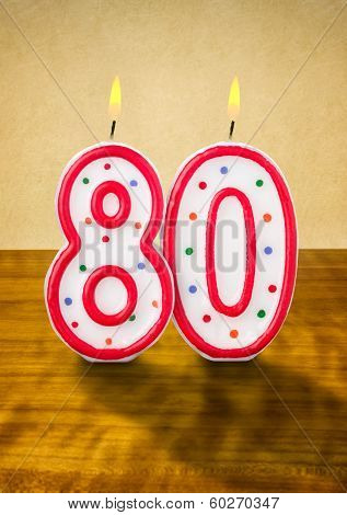 Burning birthday candles number 80 on a wooden background