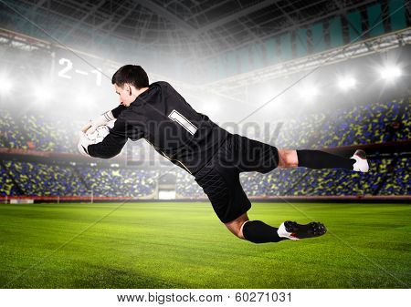 soccer or football goalkeeper is catching ball on stadium